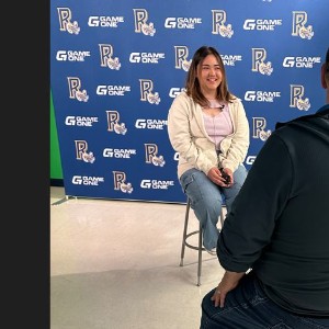 Rampart student, Kaitlyn O'Keeffe is being interviewed by local tv station, KOAA in front of a background that says, "Game One" with the Rampart logo